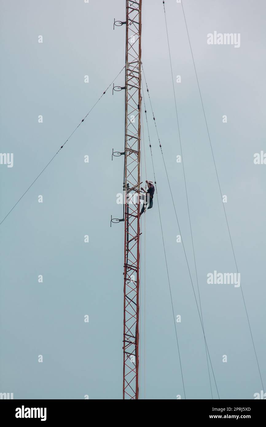 Des hommes grimpent sur l'antenne. Pour installer le périphérique Banque D'Images