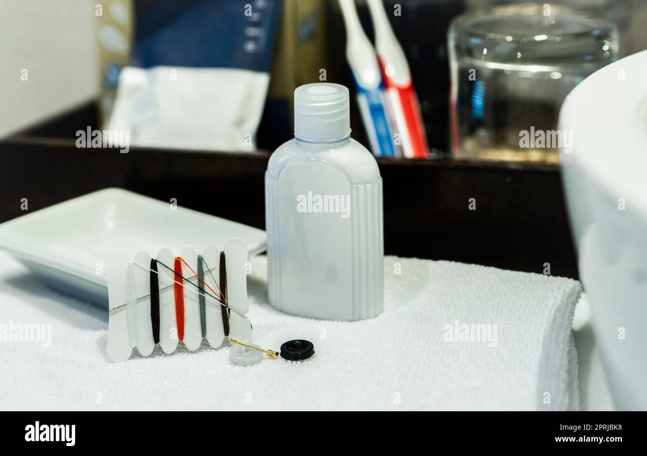 Kit de couture et crème pour les mains dans la salle de bains de l'hôtel. Petit kit de réparation de filetage portable avec aiguilles, boutons, filetages et broches de sécurité pour l'hôtel et le voyage. Kit de couture ECO. Kit de réparation de vêtements. Banque D'Images