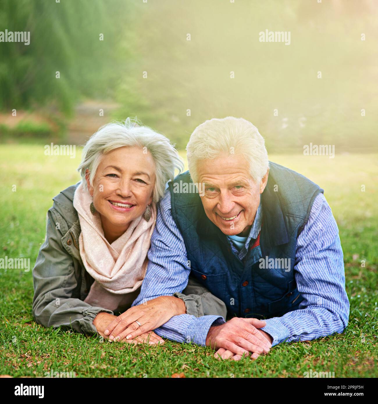 Vivre le rêve de la retraite. Portrait d'un heureux couple senior couché sur l'herbe ensemble dans le parc. Banque D'Images