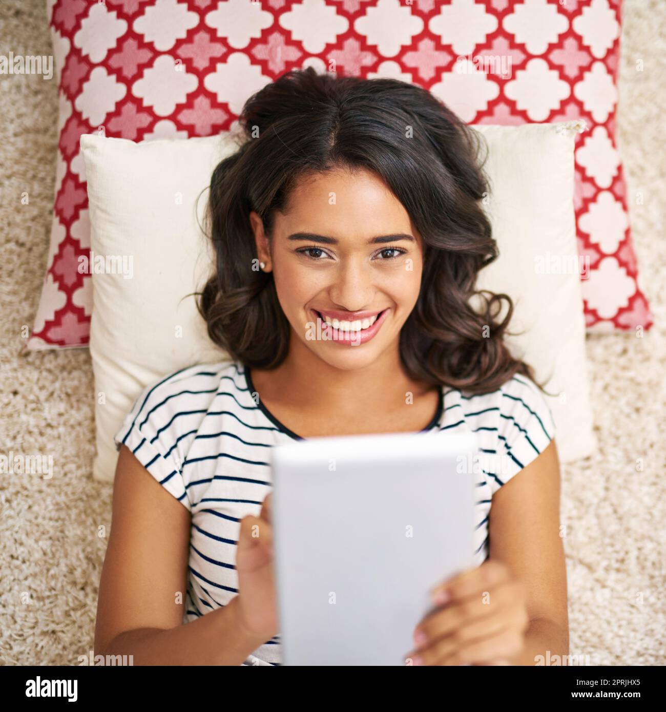 Mes flux sociaux sont bourdonnants. Portrait en grand angle d'une jeune femme utilisant sa tablette tout en se relaxant à la maison. Banque D'Images