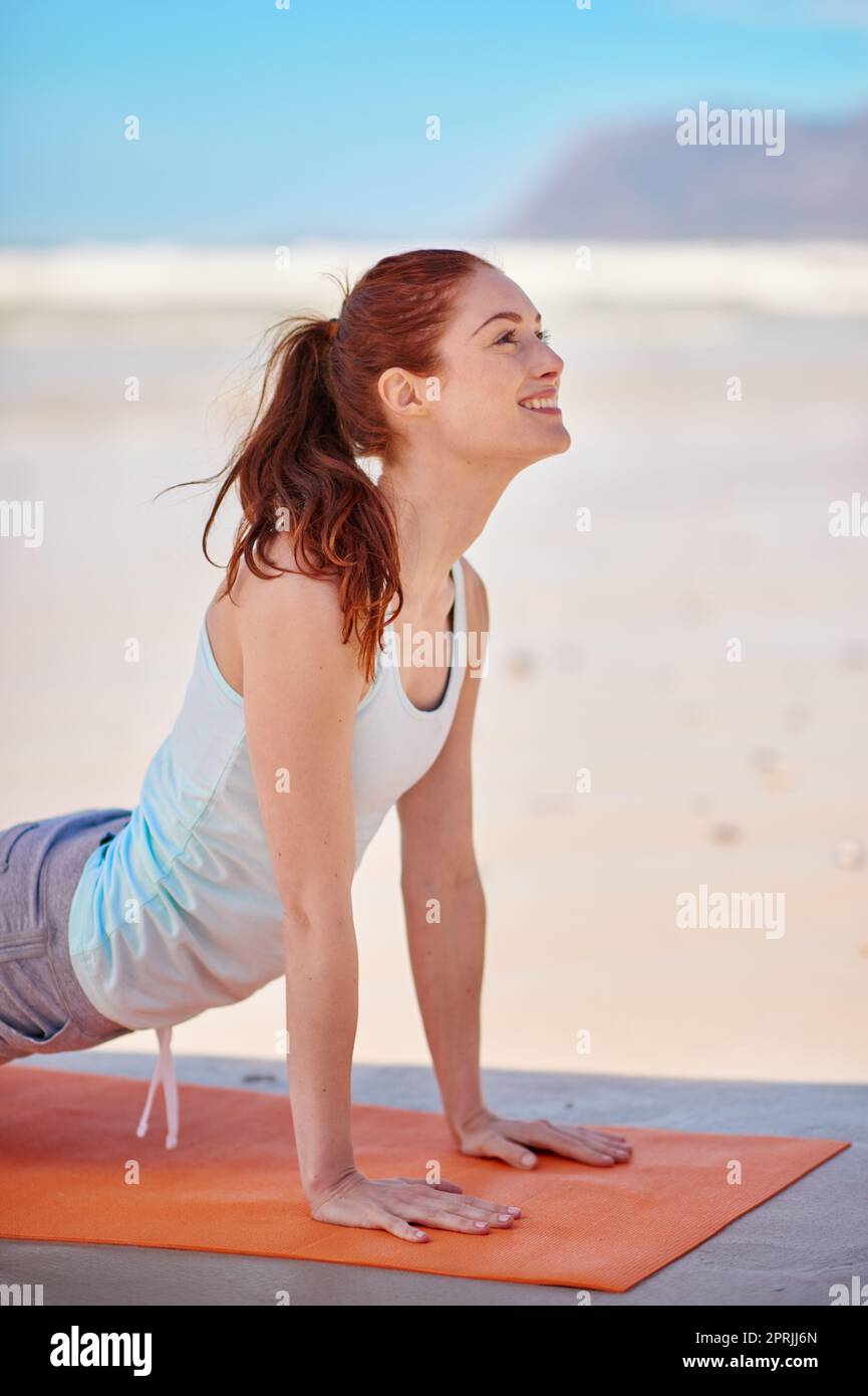 Créez une vie qui se sent bien à l'intérieur. Une jeune femme pratiquant sa routine de yoga à la plage. Banque D'Images