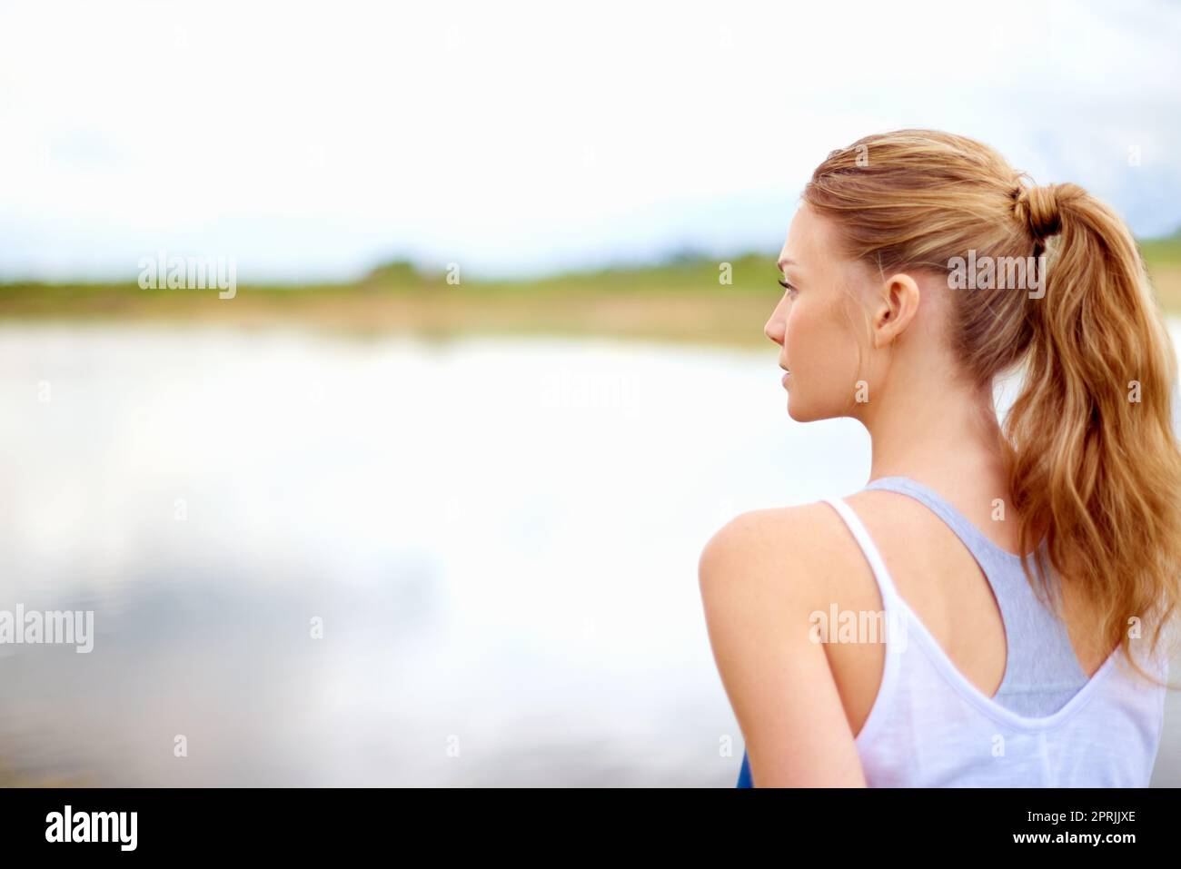 Allez être seul avec vos pensées. Photo d'une jeune femme regardant un lac tout en faisant du yoga. Banque D'Images