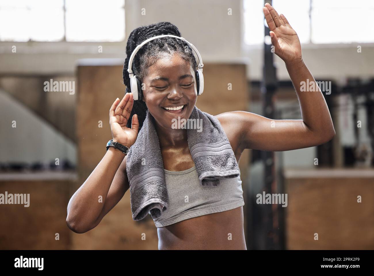 Un athlète heureux chantant et dansant avec un casque dans une salle de sport après la remise en forme, l'exercice et l'entraînement. Femme gaie transpirant s'amuser avec de la musique après la santé et le bien-être cardio-entraînement dans un club sportif Banque D'Images