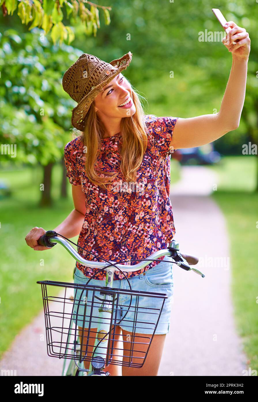 Une jeune femme qui prend un selfie alors qu'elle est à l'extérieur pour une balade en vélo dans le parc. Banque D'Images