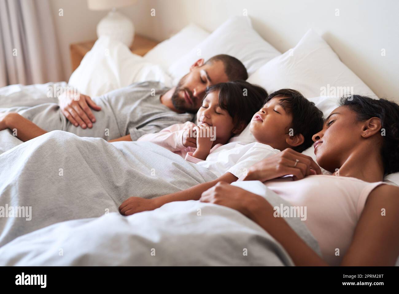 Ne nous réveillez pas. une belle jeune famille de quatre personnes dormait  rapidement au lit dans leur chambre à la maison Photo Stock - Alamy