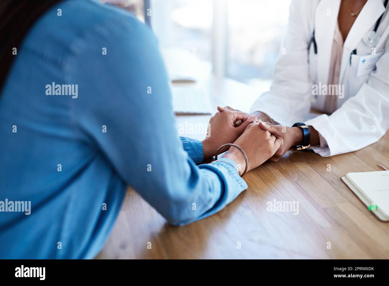 Mettre le cœur dans les soins de santé. un médecin tenant les mains d'un patient dans sa salle de consultation Banque D'Images