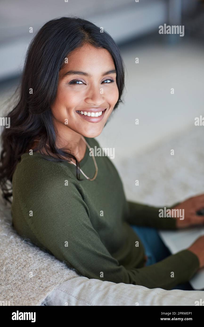 Le confort de la maison. Portrait d'une jeune femme attrayante assise sur le canapé à la maison. Banque D'Images