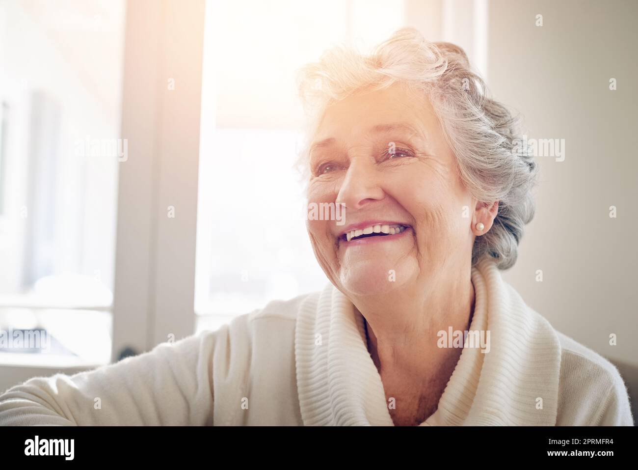 Réfléchir à certains des meilleurs moments de sa vie. Une femme âgée regardant à la maison. Banque D'Images