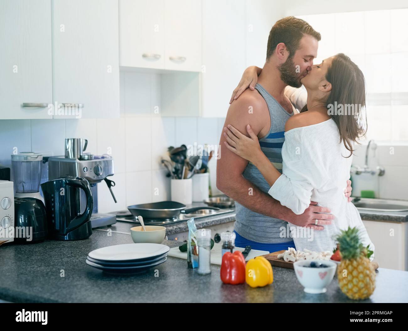 Bonjour à Vous aussi. un jeune couple aimant embrassant en se tenant dans leur cuisine à la maison. Banque D'Images