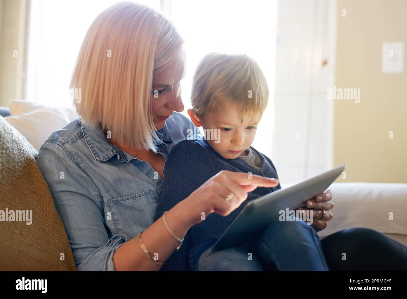 Les mamans lui ont téléchargé une nouvelle application sécurisée sur laquelle jouer. Une mère et un fils utilisant une tablette numérique ensemble à la maison. Banque D'Images