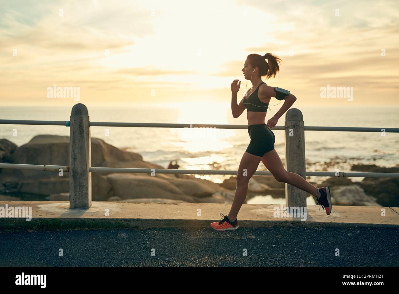 Continuez à mettre un pied devant l'autre. Une jeune femme sportive qui court le long de l'esplanade. Banque D'Images