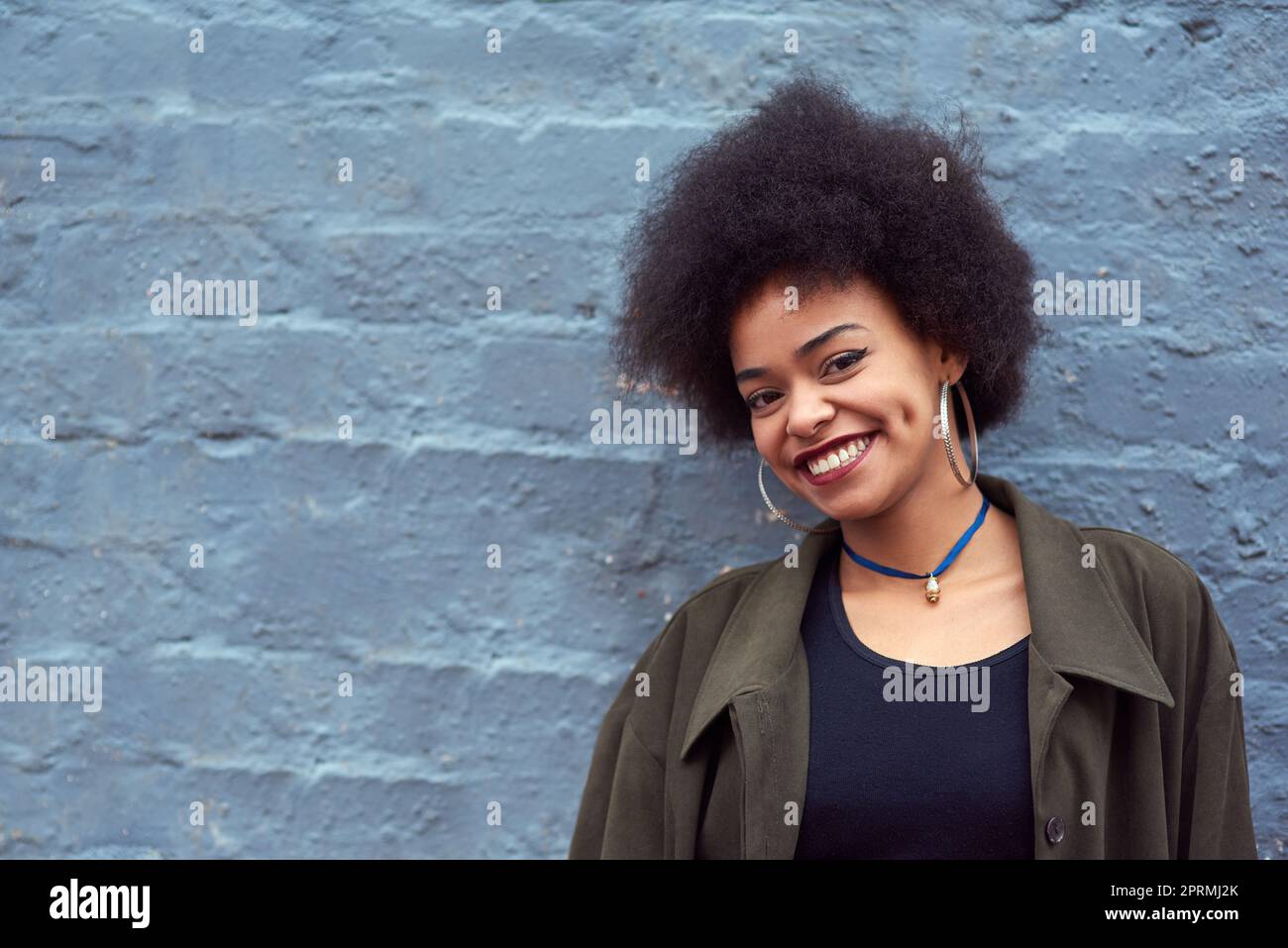 La vie ne devrait pas être plus belle. Portrait d'une jeune femme heureuse debout contre un mur de briques. Banque D'Images