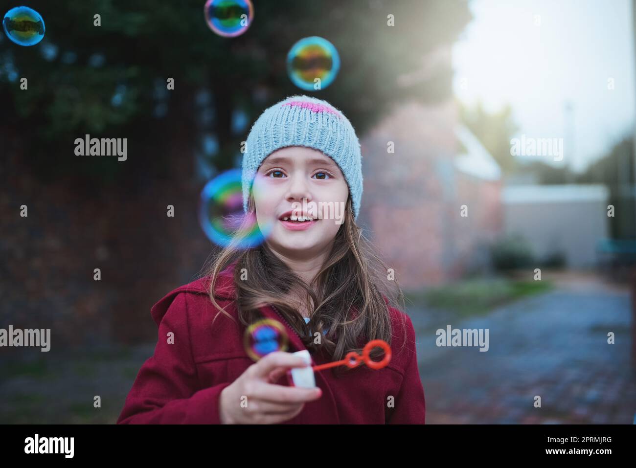 Regardez-les éclater. Une petite fille soufflant des bulles à l'extérieur. Banque D'Images