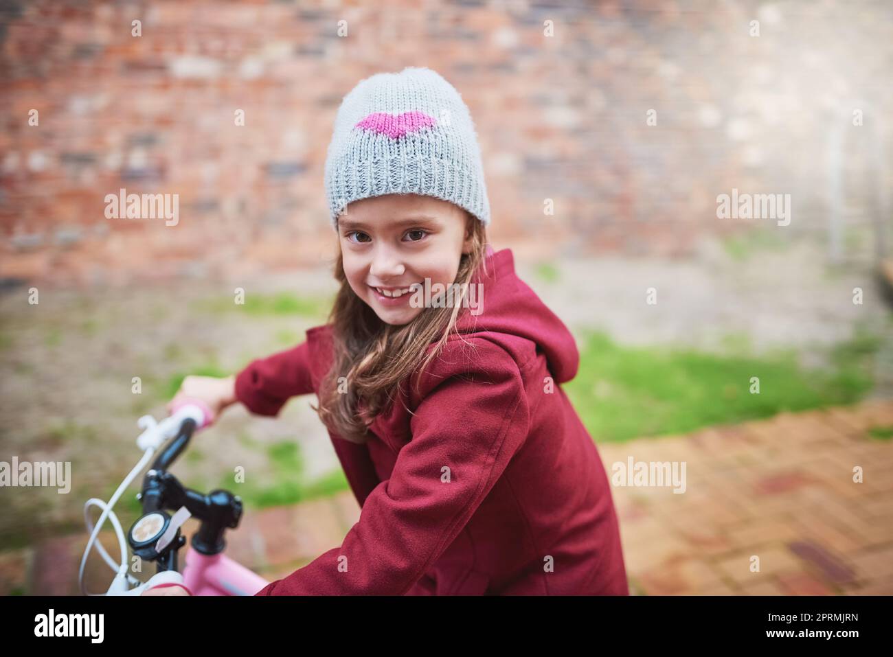 Oh, quel plaisir que d'être un enfant. Portrait d'une petite fille à vélo à l'extérieur. Banque D'Images