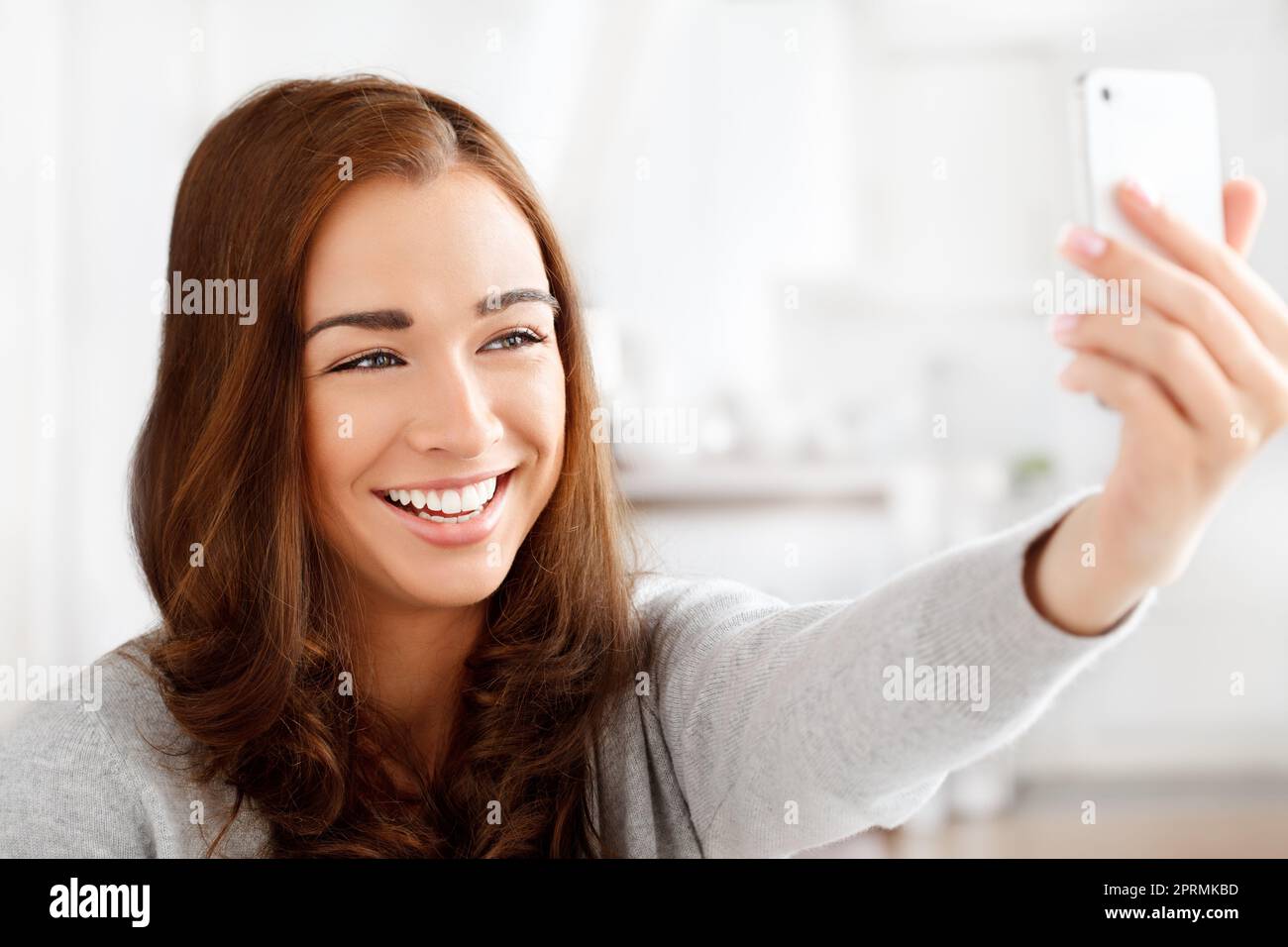 Selfie, téléphone et réseaux sociaux avec une jeune femme prenant une photo ou une photo sur son smartphone pour son statut en ligne ou son calendrier. Bonne femme posant pour une photo dans une maison avec la technologie mobile Banque D'Images