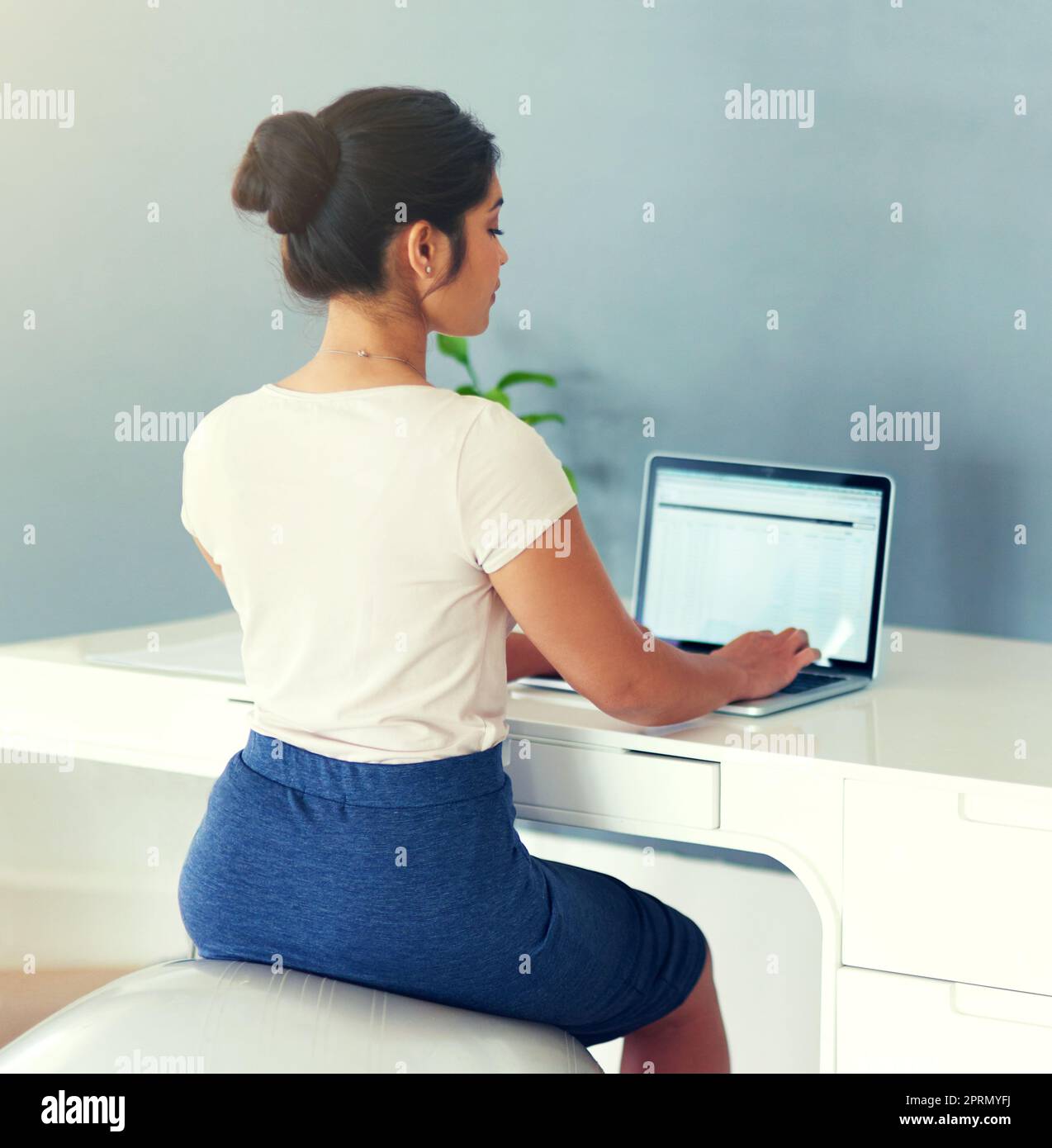 L'alternative ergonomique à la chaise de bureau. Une jeune femme d'affaires travaillant sur son ordinateur portable à la maison. Banque D'Images