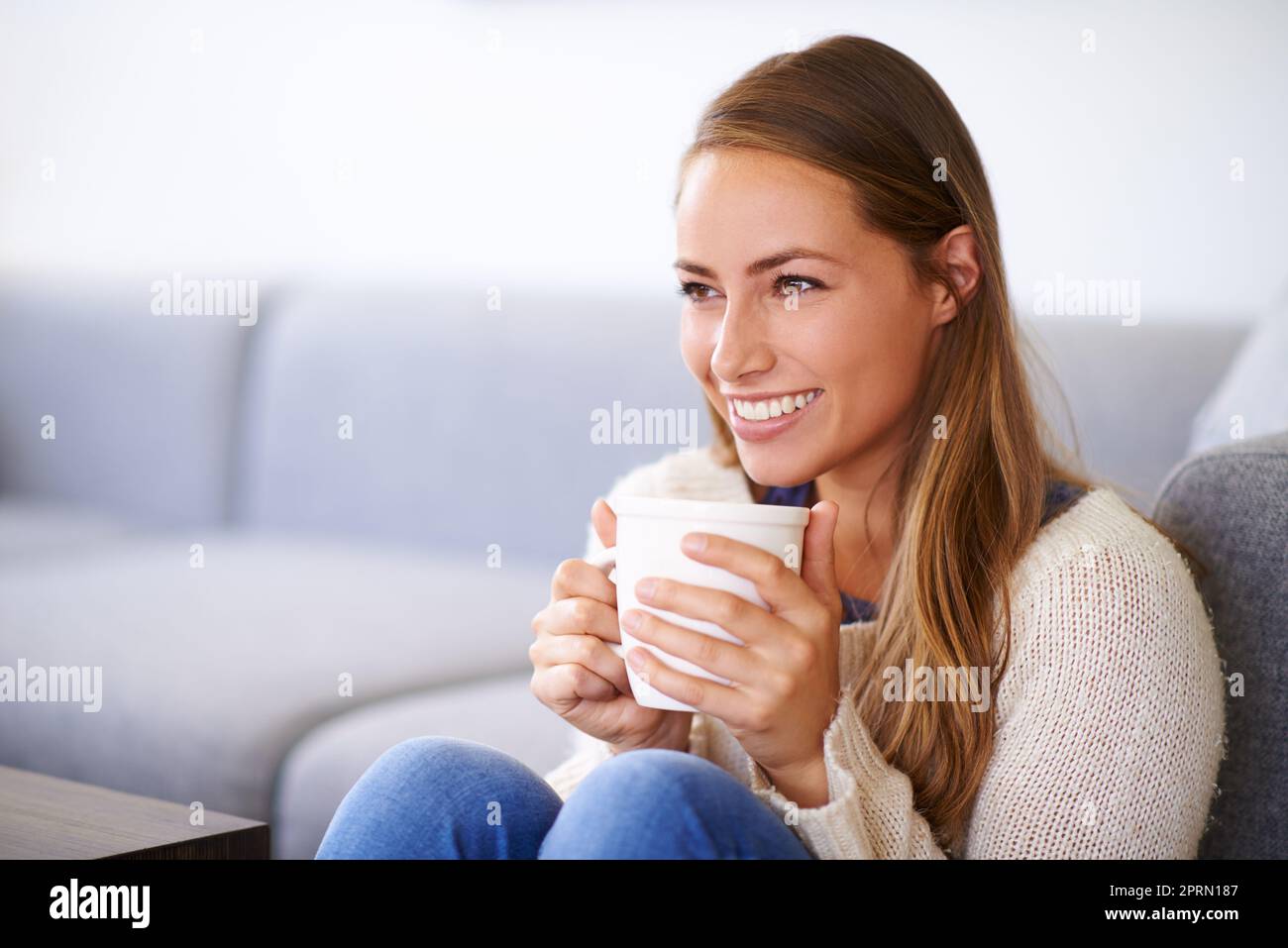 Il n'y a pas d'endroit comme à la maison. Une jeune femme ayant un café à la maison. Banque D'Images