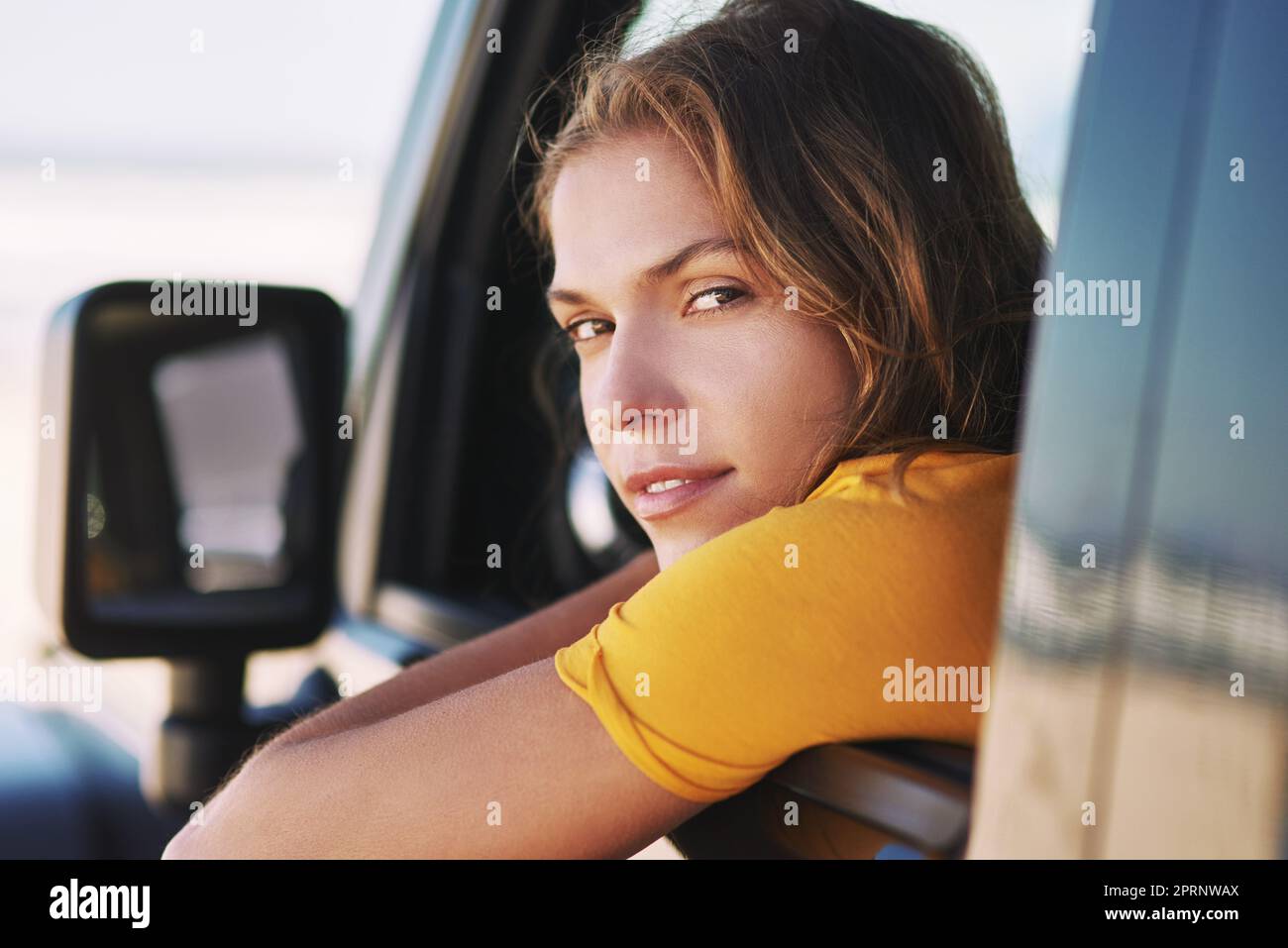 Partez en voyage. Portrait d'une jeune femme assise dans sa voiture. Banque D'Images