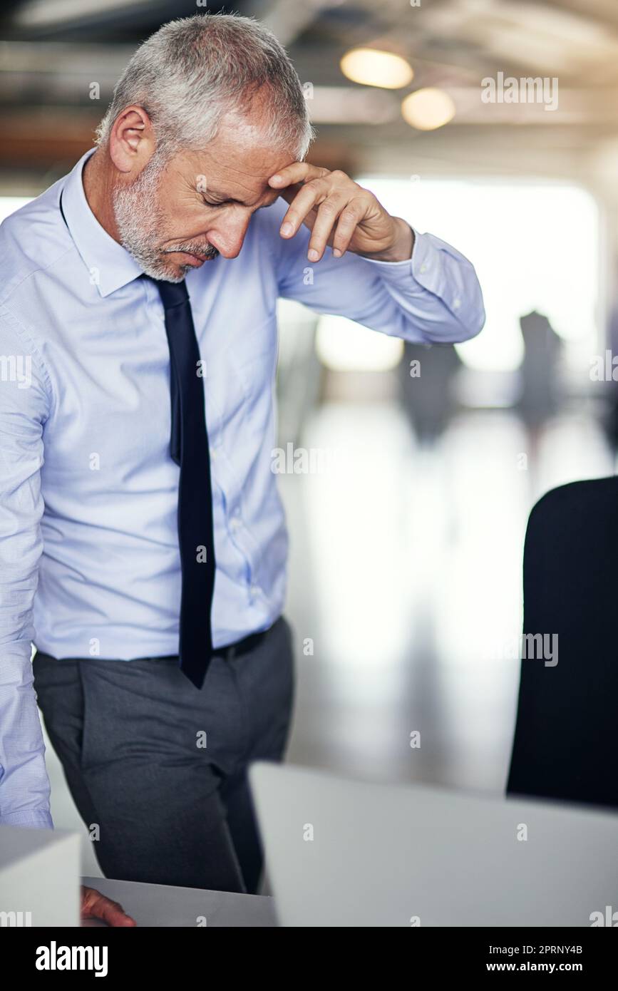 Sous pression... un homme d'affaires mature qui semble stressé pendant qu'il travaille dans son bureau. Banque D'Images