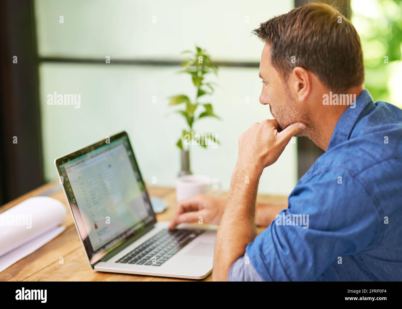 Concentré sur la tâche à accomplir. Un homme travaillant sur son ordinateur portable à la maison. Banque D'Images