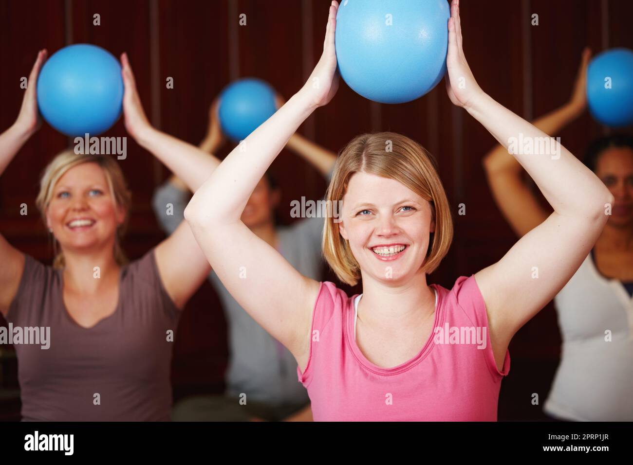 Pilates, fitness et entraînement d'une femme heureuse dans un cours de santé et de bien-être dans un studio de yoga. Entraînement de balle et exercice d'une femme de détente d'Allemagne avec un sourire essayant d'être en bonne santé dans une salle de gym Banque D'Images