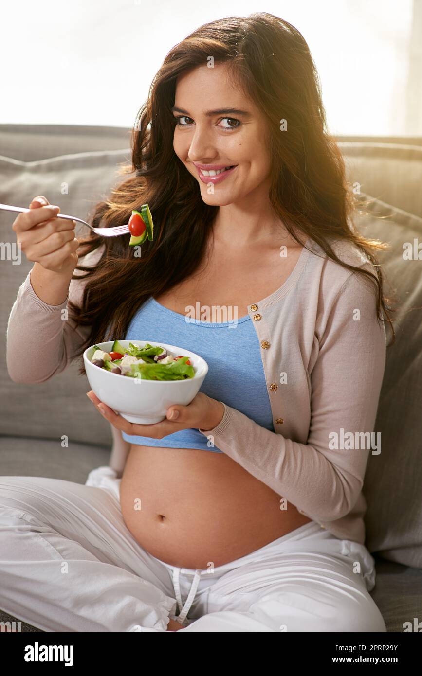 Mon bébé aime quand je mange des aliments biologiques. Une femme enceinte qui mange une salade saine à la maison. Banque D'Images