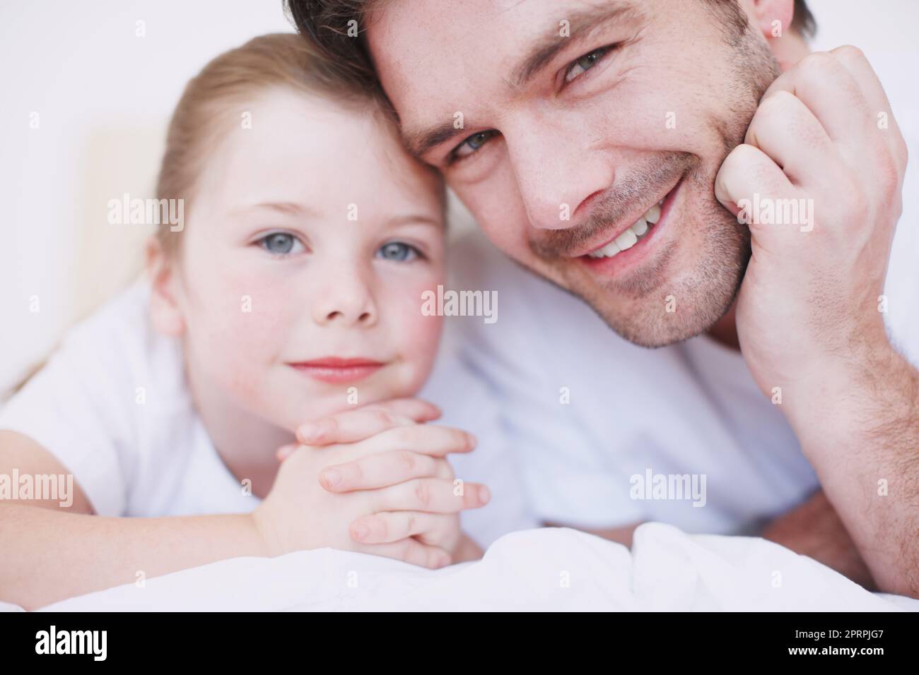 Sa fille est si spéciale pour lui. Un père et sa jeune fille sont côte à côte sur un lit. Banque D'Images