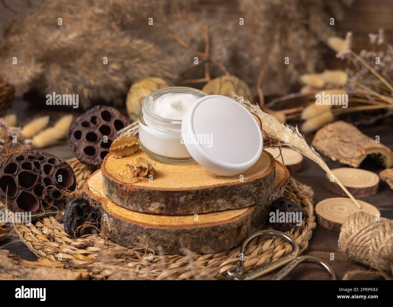 Ouvert verre crème pot sur bois près des décorations naturelles de près. Maquette d'emballage Banque D'Images