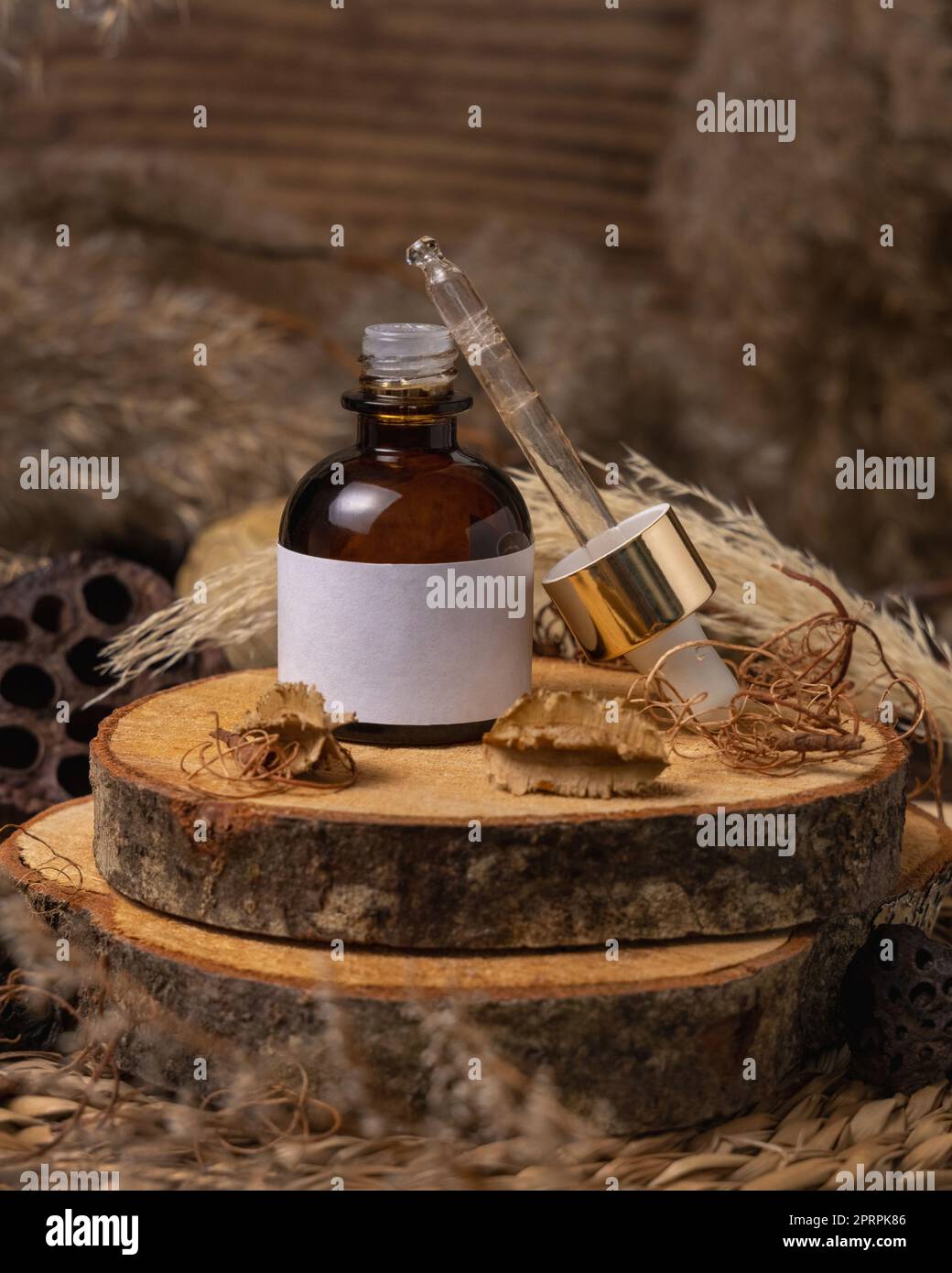 Ouverture de la bouteille compte-gouttes cosmétique sur bois près des décorations de boho naturel gros plan. Maquette d'étiquette Banque D'Images
