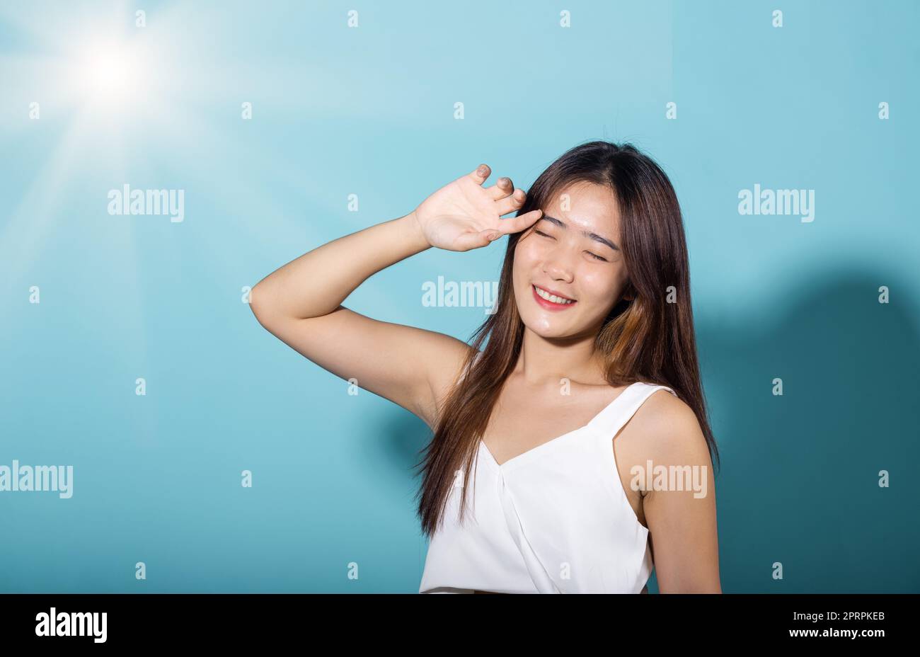 Asiatique jeune femme main vers le haut couverture visage protéger la lumière du soleil et le sourire UV Banque D'Images