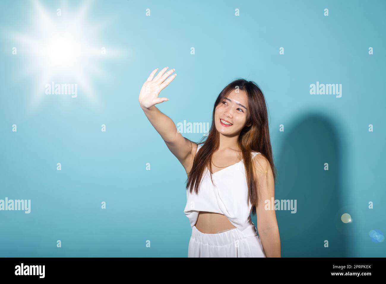 Asiatique jeune femme main vers le haut couverture visage protéger la lumière du soleil et le sourire UV Banque D'Images
