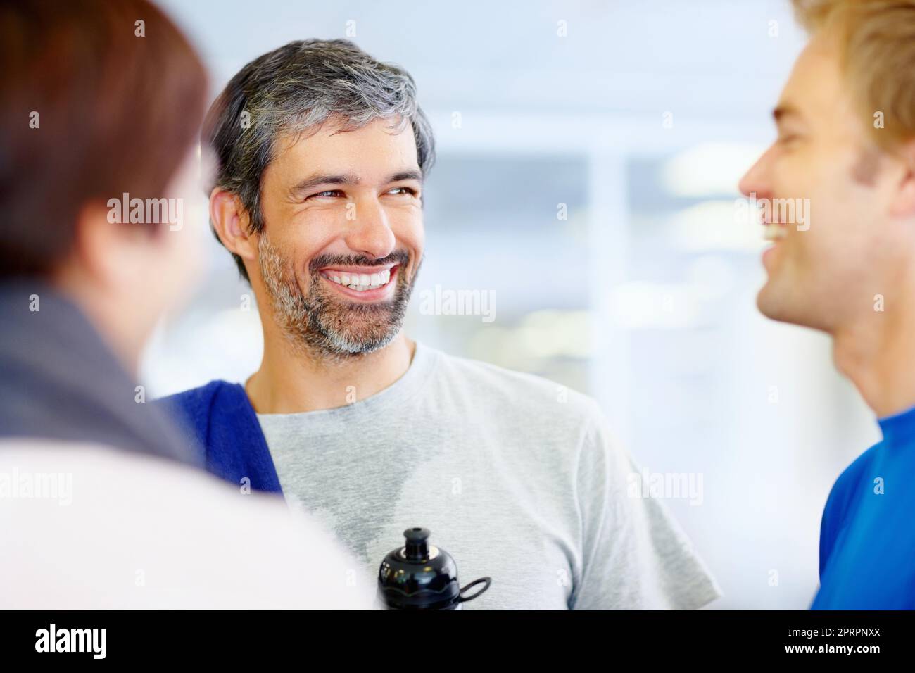 Amis parlant après l'exercice. Portrait d'un homme mûr souriant parlant avec des amis au centre de fitness. Banque D'Images