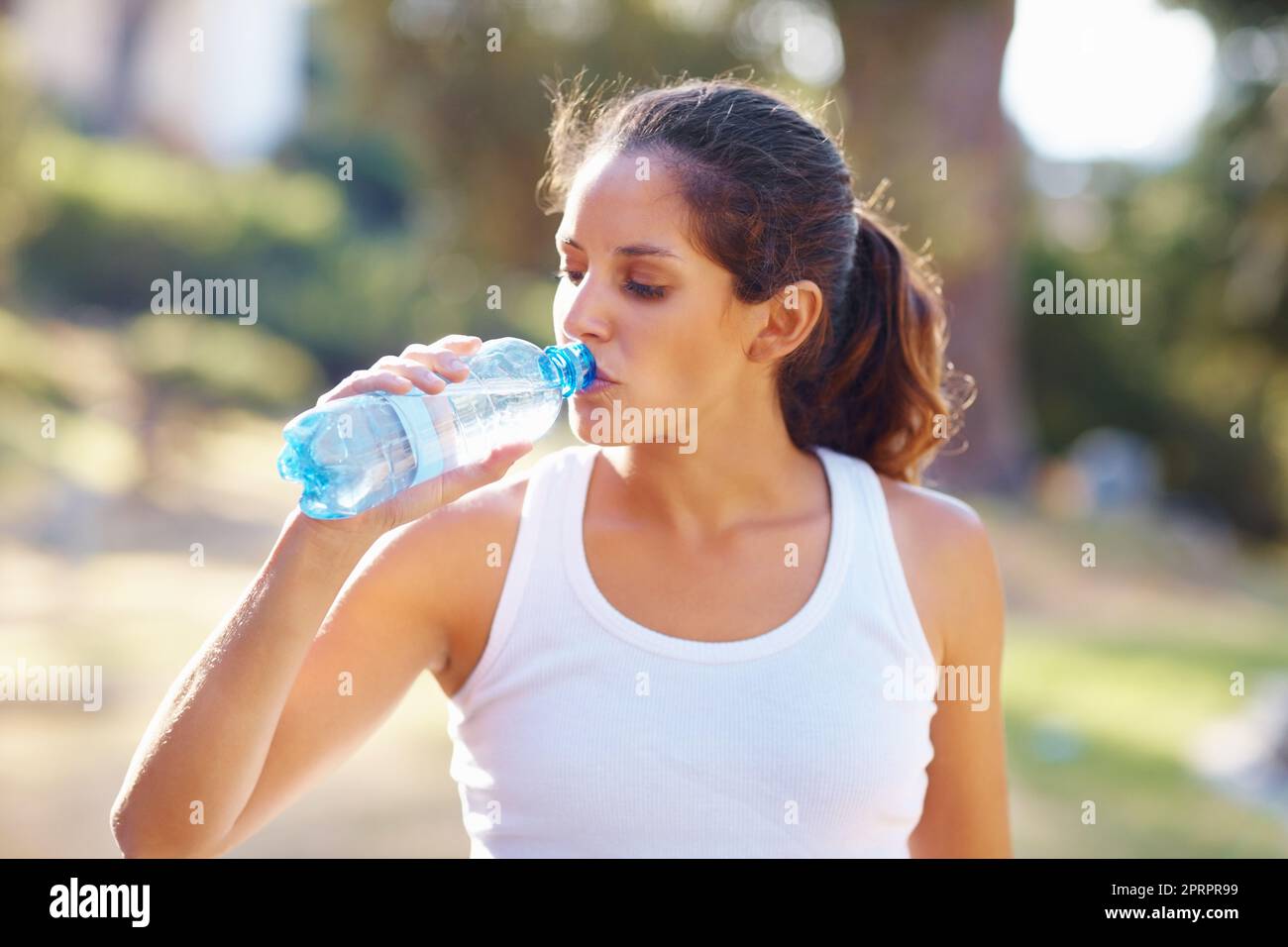 Femme buvant une bouteille d'eau après un jogging. Portrait d'une femme attrayante ayant une bouteille d'eau après un jogging. Banque D'Images