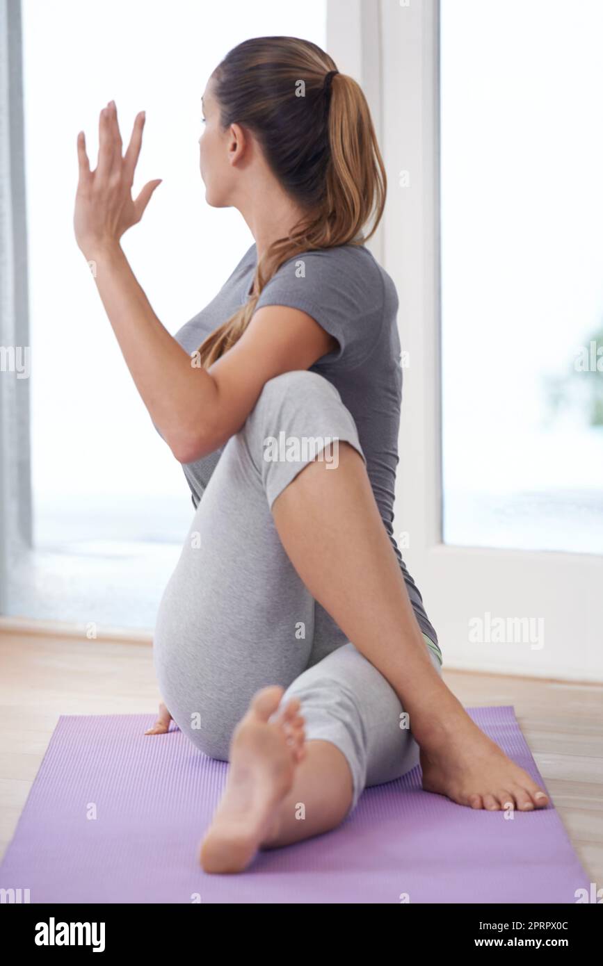 Se concentrer sur le corps et l'esprit. Une jeune femme faisant du yoga sur son tapis d'exercice. Banque D'Images