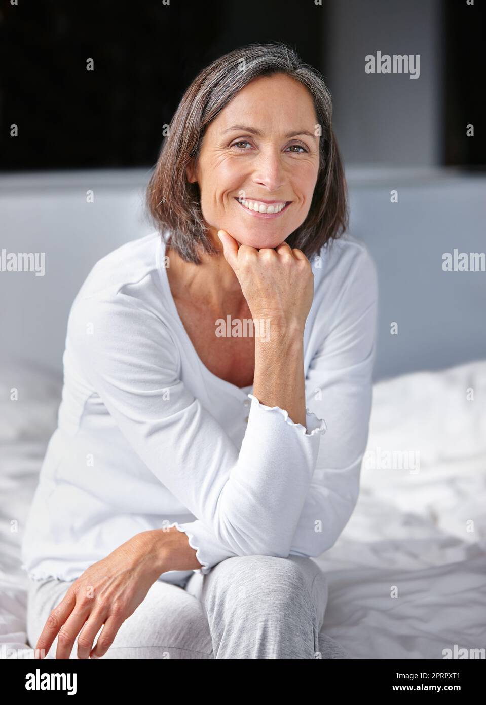 Je me suis réveillé en me sentant super ce matin. Portrait d'une belle femme mûre assise sur son lit. Banque D'Images