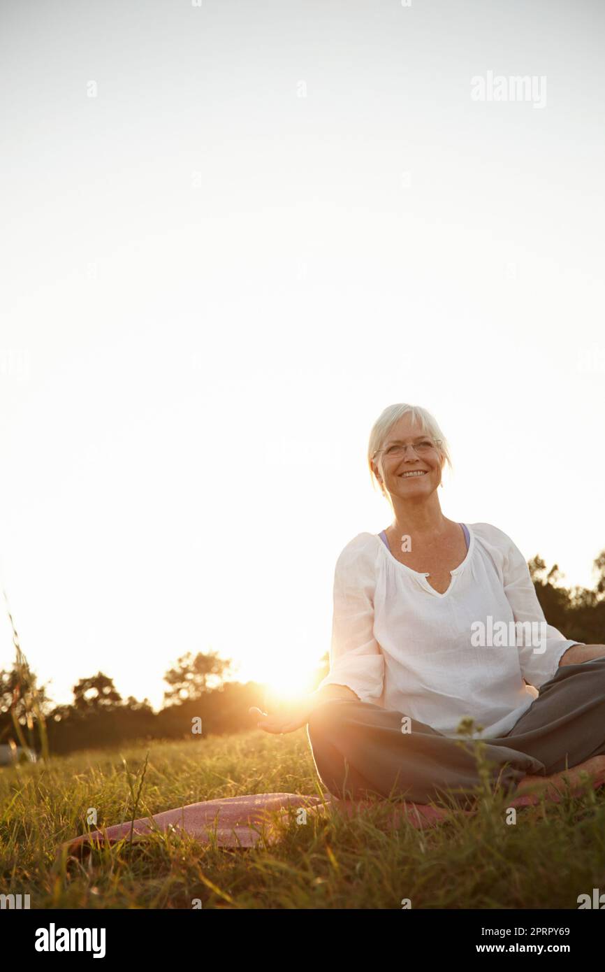 Faire le temps de méditer. Une femme mûre attrayante faisant du yoga dans la nature. Banque D'Images