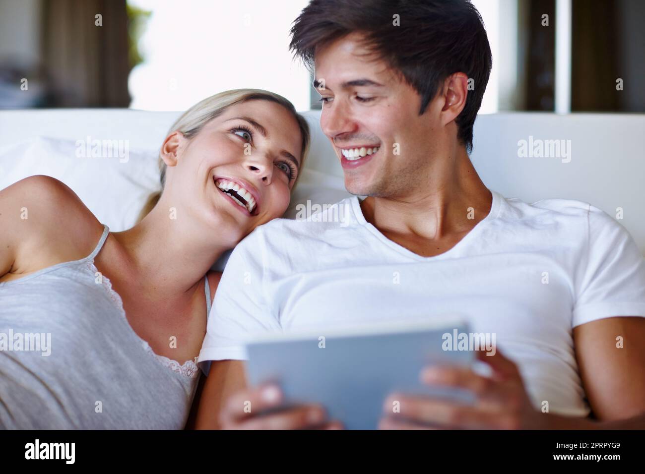 Réveillez-vous et brillez en ligne. Un couple heureux allongé au lit et utilisant une tablette numérique ensemble. Banque D'Images