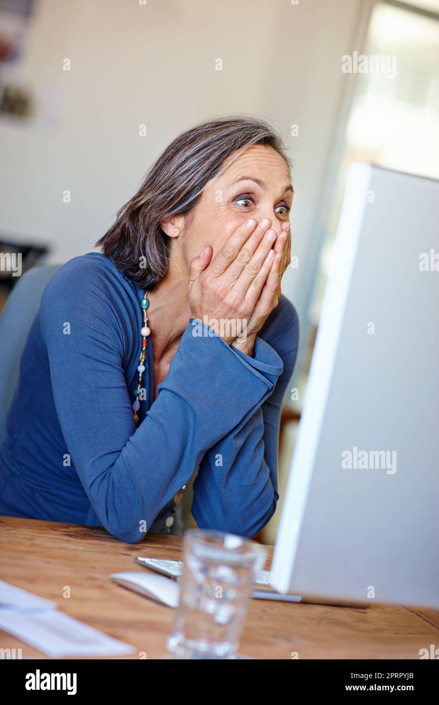 Je ne peux pas croire mes yeux. Une femme mature design professionnel regardant excité tout en travaillant à son ordinateur Banque D'Images