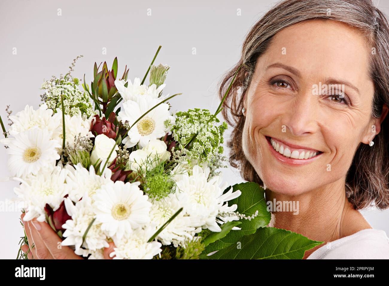 Chaque femme aime recevoir des fleurs. Portrait court en studio d'une belle femme mûre tenant un bouquet de fleurs Banque D'Images
