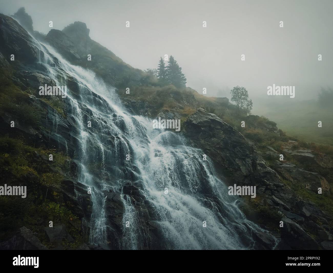 Cascade de Capra sur la route transfagarasan dans les Carpates roumains. Scène idyllique avec une grande rivière coulant à travers les rochers dans un matin d'automne brumeux Banque D'Images