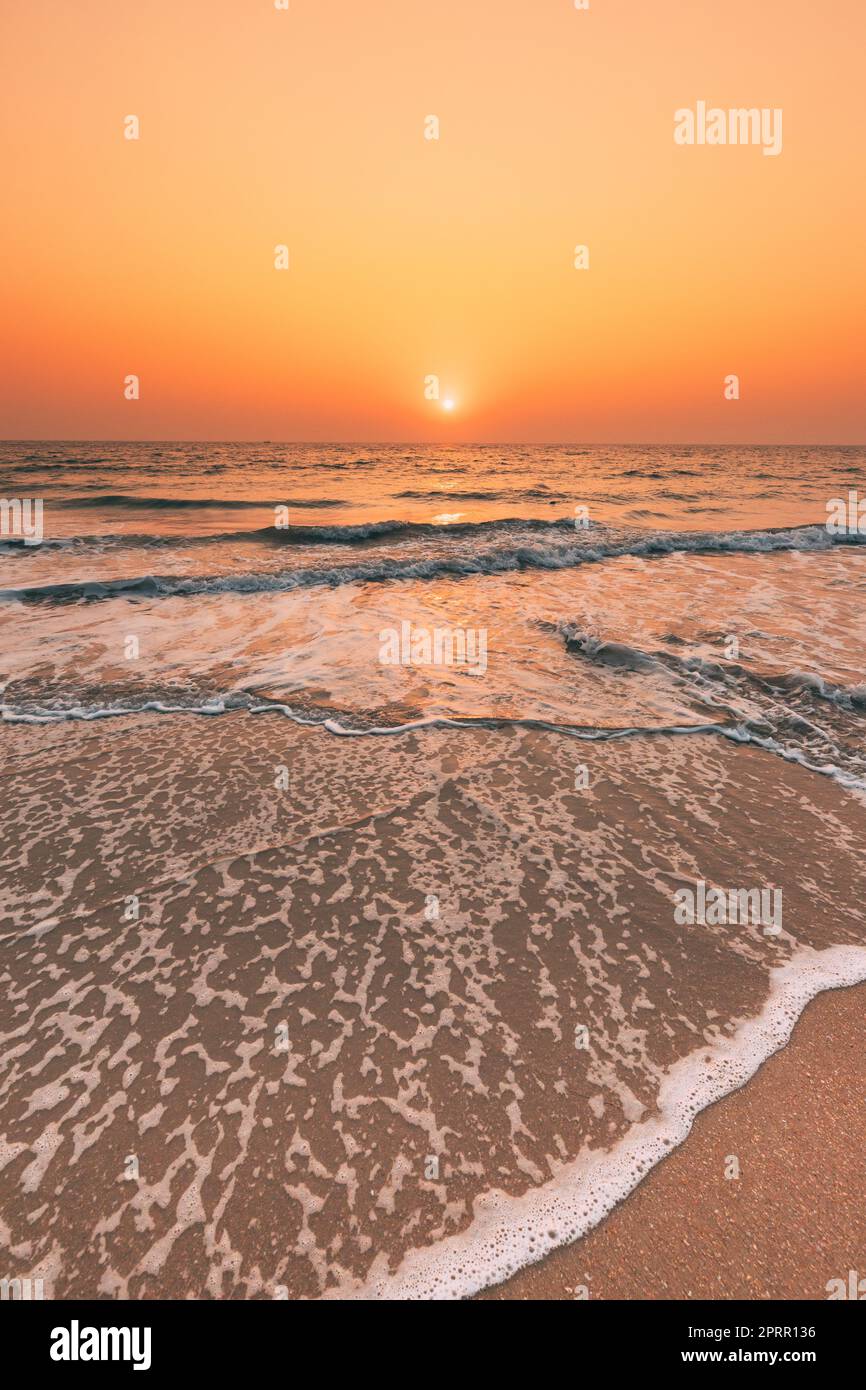 Coucher de soleil au-dessus de la mer. Ciel lever de soleil naturel couleurs chaudes sur la mer Ripple. Eau de mer mousse lavage Sandy Beach au coucher du soleil Banque D'Images