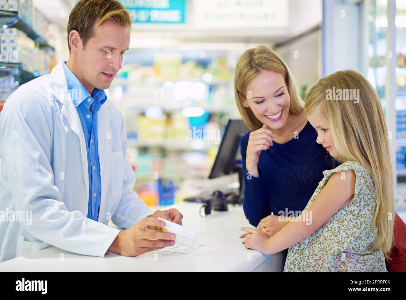 Cela va faire l'affaire. Un pharmacien donnant des médicaments à une mère et à une fille Banque D'Images