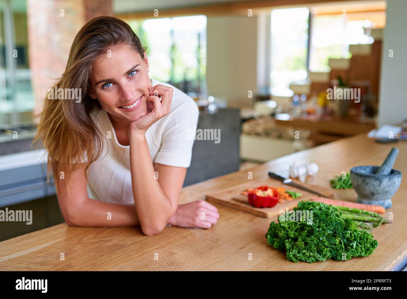 J'ai besoin d'un autre ingrédient... Portrait d'une jeune femme attirante qui s'appuie sur son comptoir de cuisine. Banque D'Images