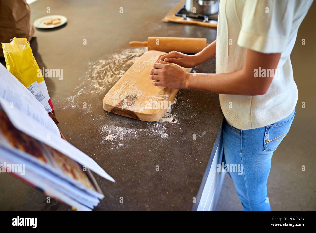 Essayer une nouvelle recette. Une jeune femme pétrit de la pâte dans sa cuisine. Banque D'Images