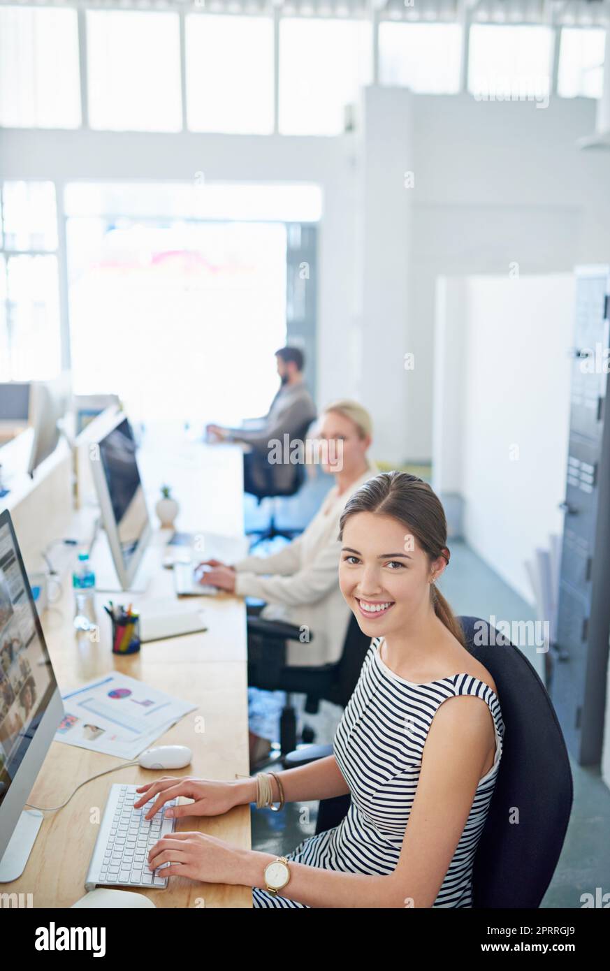 Partenaires sur le nouveau projet. Portrait d'une jeune employée de bureau assise à son poste de travail dans un bureau. Banque D'Images
