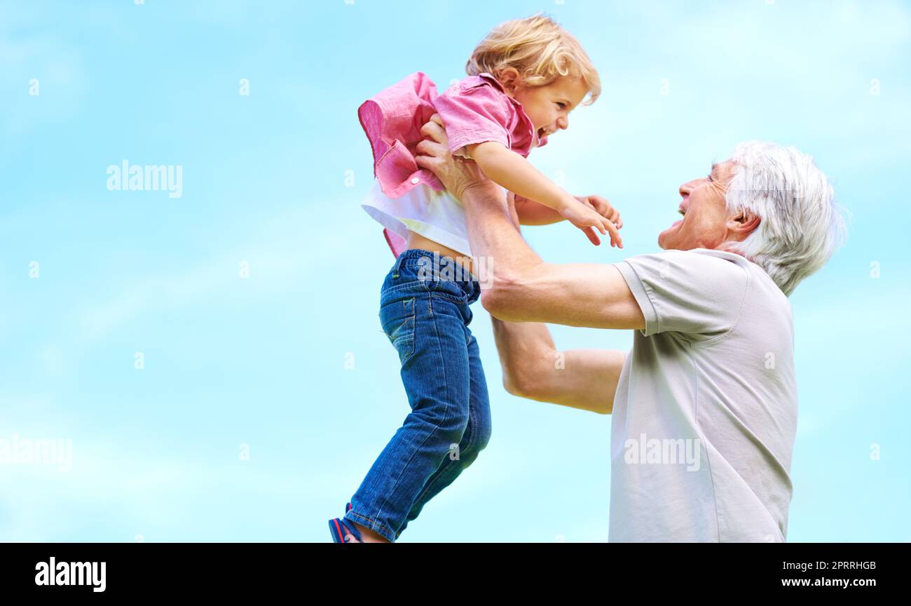 Les petits-enfants sont une compensation pour l'âge croissant. Un grand-père heureux jouant avec son petit-fils et le levant dans les airs Banque D'Images