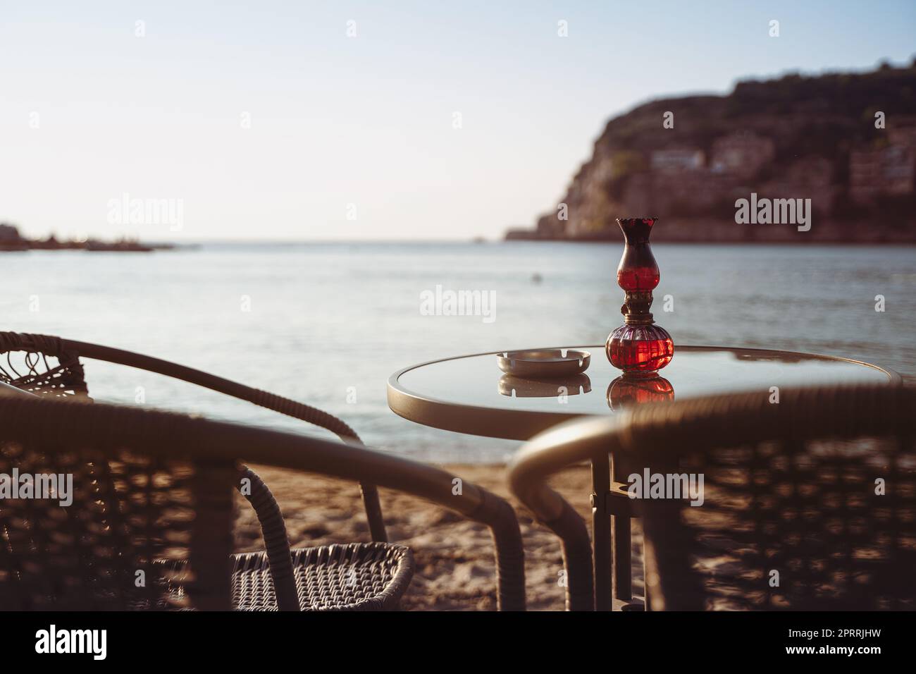 table de café vide et chaises sur la plage de sable avec cendrier et bougie lumière en face du golf de mer avec ciel clair avant le coucher du soleil Banque D'Images