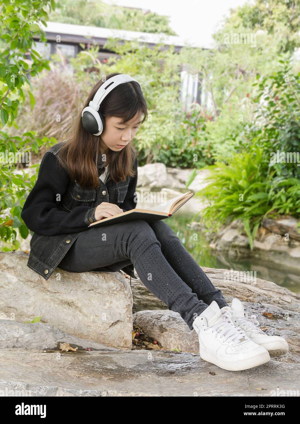 Young Girl reading book et écouter de la musique in park Banque D'Images
