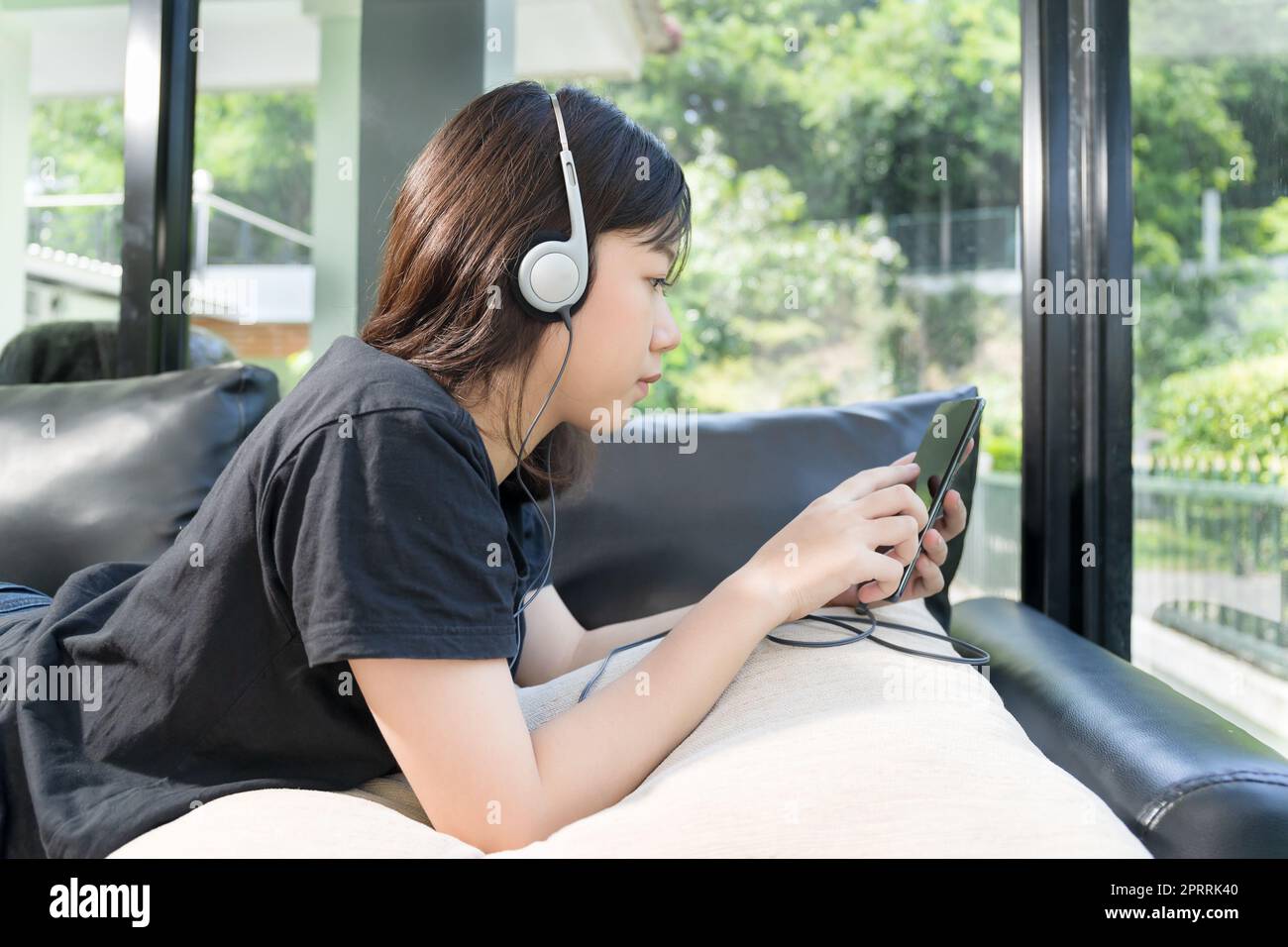 Une jeune fille qui écoute de la musique à partir d'un téléphone portable dans sa vie chambre Banque D'Images