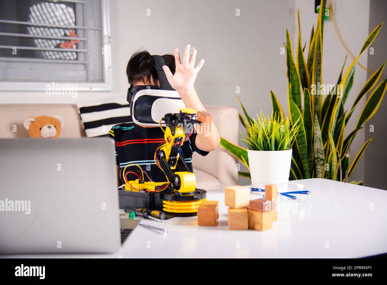 Enfant asiatique utilisant des lunettes VR sur le bras robotique dans l'atelier Banque D'Images